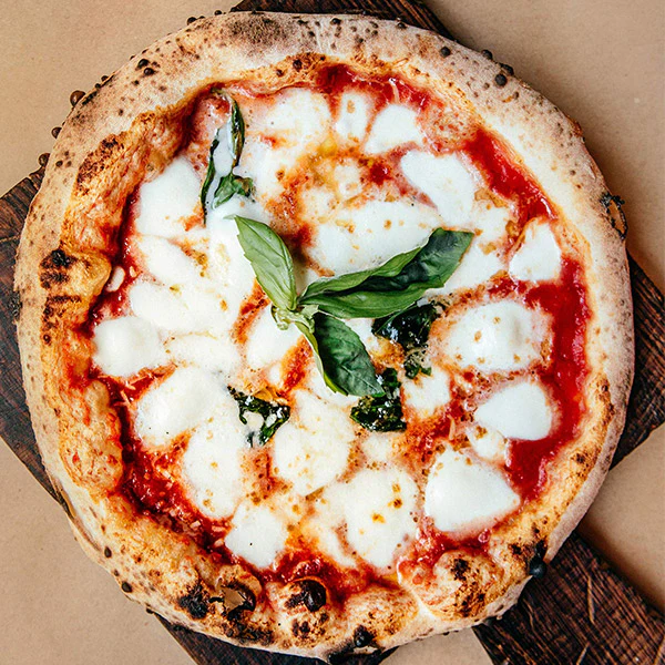 Comparaison entre une pizza napolitaine classique et une pizza Contemporanea sur planche en bois